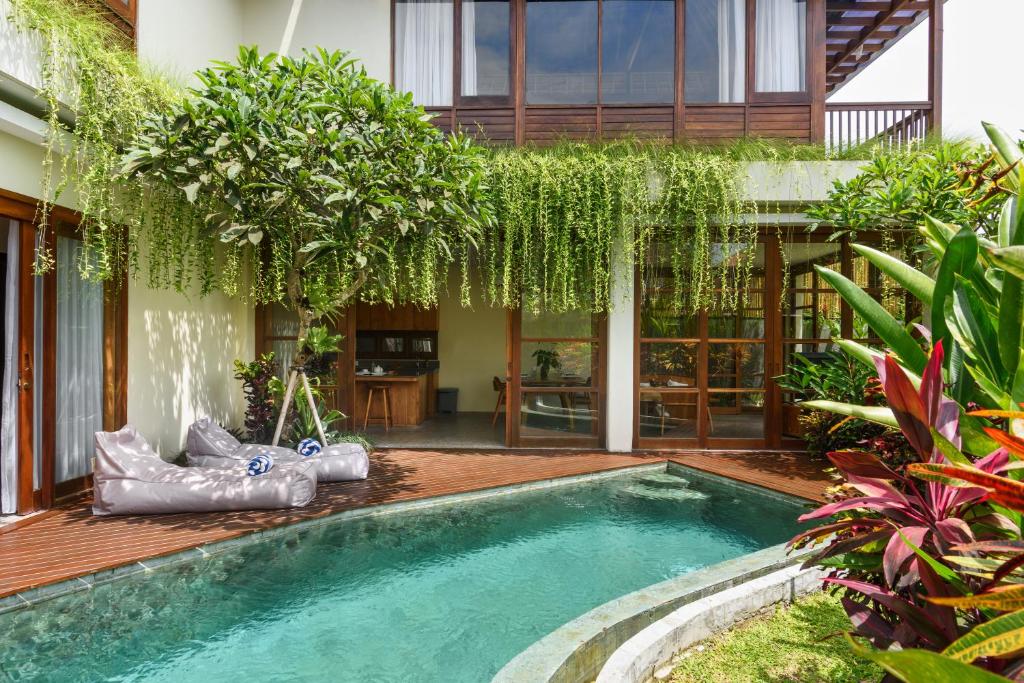 a swimming pool in front of a house at Anandathu Villas in Canggu