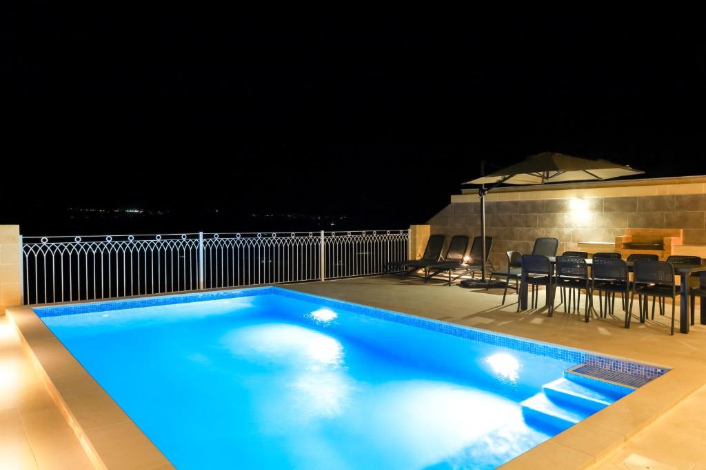 a swimming pool at night with a table and chairs at Magnifica Holiday Home with Jacuzzi hot tub and pool in Xagħra