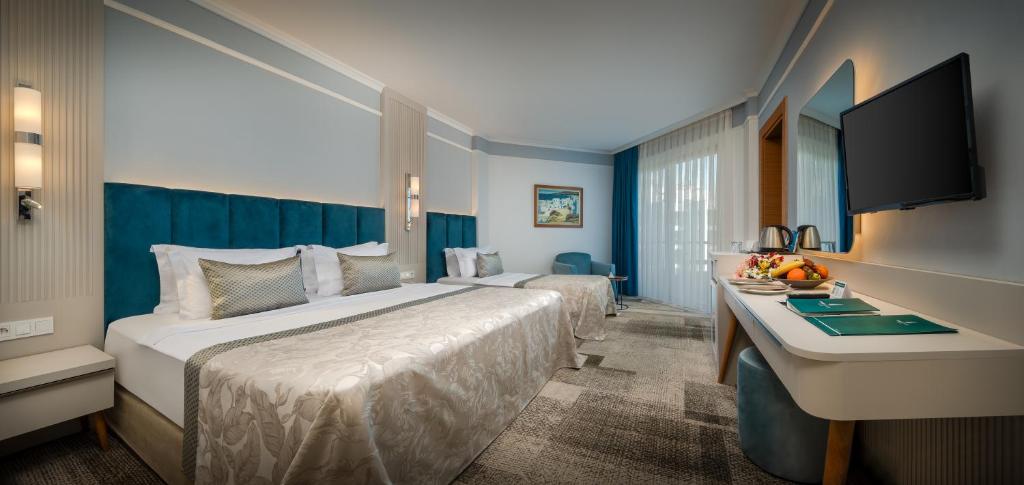 a hotel room with a large bed and a desk at Pine Beach Belek in Belek