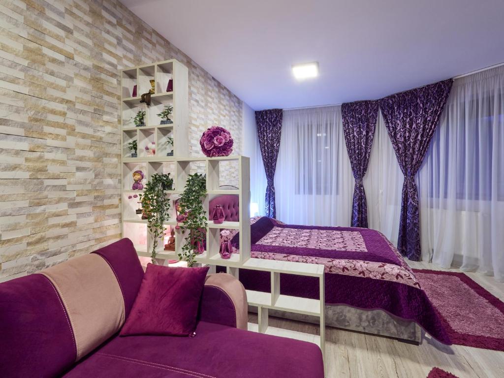 a bedroom with a bed and a purple couch at Purple Suite in Sinaia
