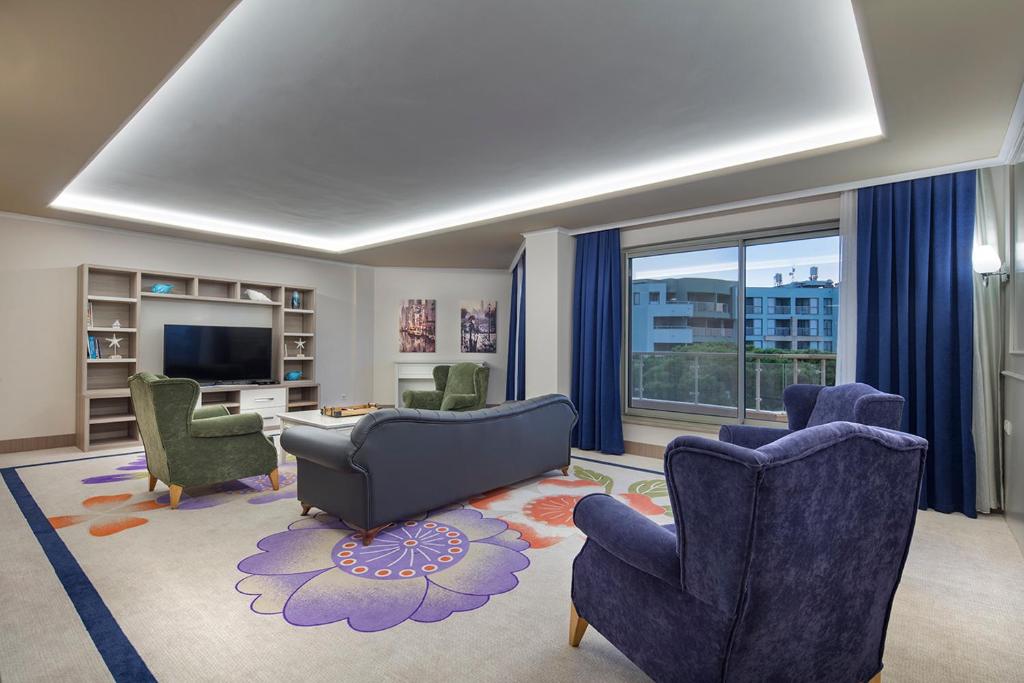 a living room with chairs and a couch and a tv at Pine Beach Belek in Belek