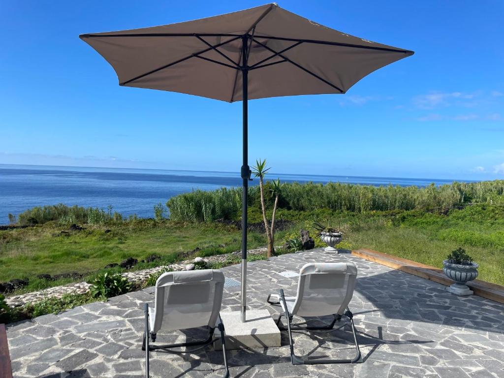two chairs sitting under an umbrella on a patio at Casa Cachalote - Ferienhaus auf den Azoren in São Caetano
