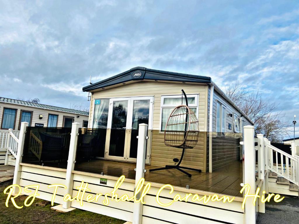 a tiny house with a porch and a swing at RJ Luxury caravan hire 2 with Hot Tub in Tattershall