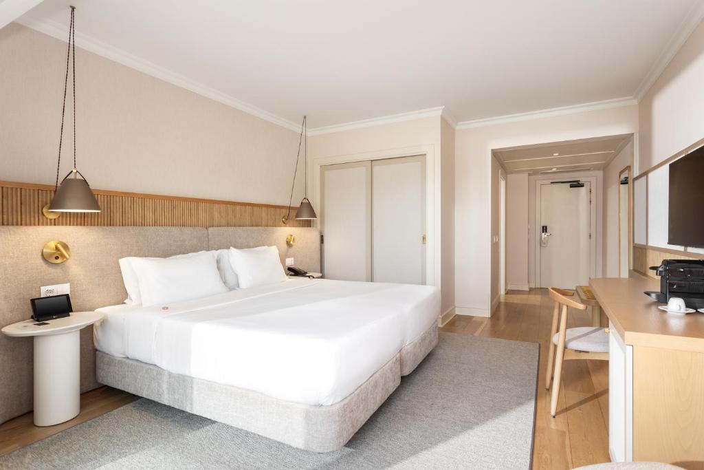 a bedroom with a large white bed and a desk at Grande Real Santa Eulalia Resort & Hotel Spa in Albufeira