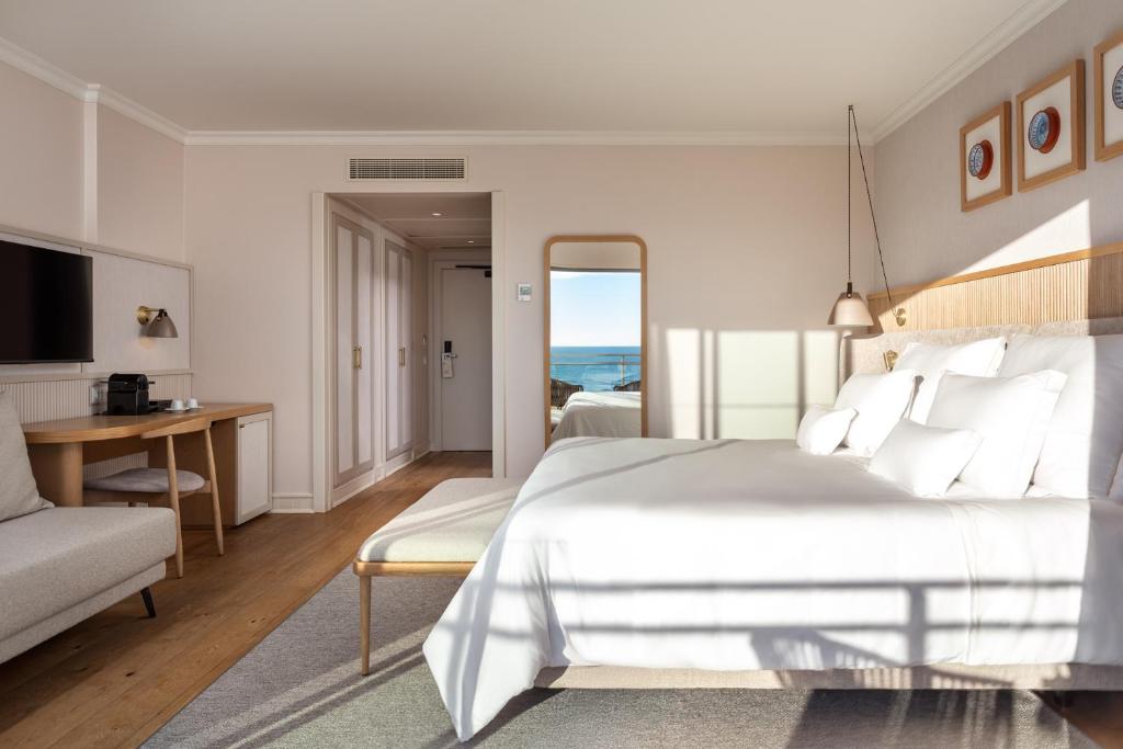 a bedroom with a large white bed and a desk at Grande Real Santa Eulalia Resort & Hotel Spa in Albufeira