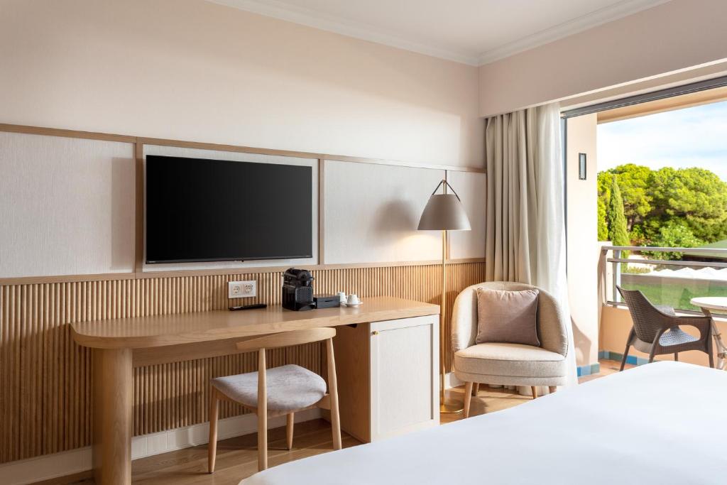 a hotel room with a desk and a tv at Grande Real Santa Eulalia Resort & Hotel Spa in Albufeira