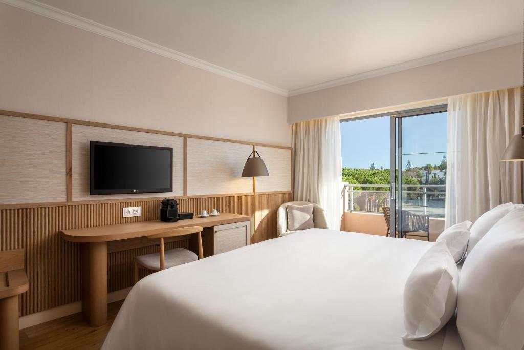 a hotel room with a bed and a desk and a television at Grande Real Santa Eulalia Resort & Hotel Spa in Albufeira