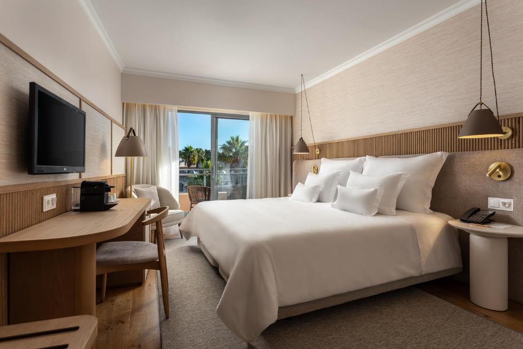 a hotel room with a large bed and a desk at Grande Real Santa Eulalia Resort & Hotel Spa in Albufeira