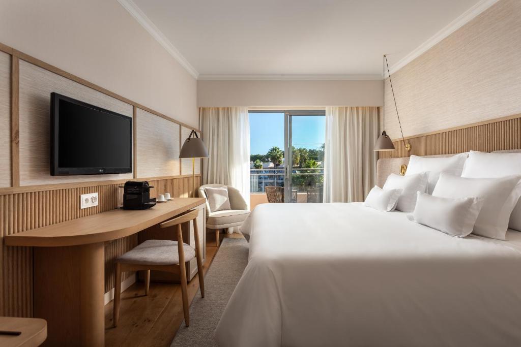 a hotel room with a bed and a desk and a television at Grande Real Santa Eulalia Resort & Hotel Spa in Albufeira