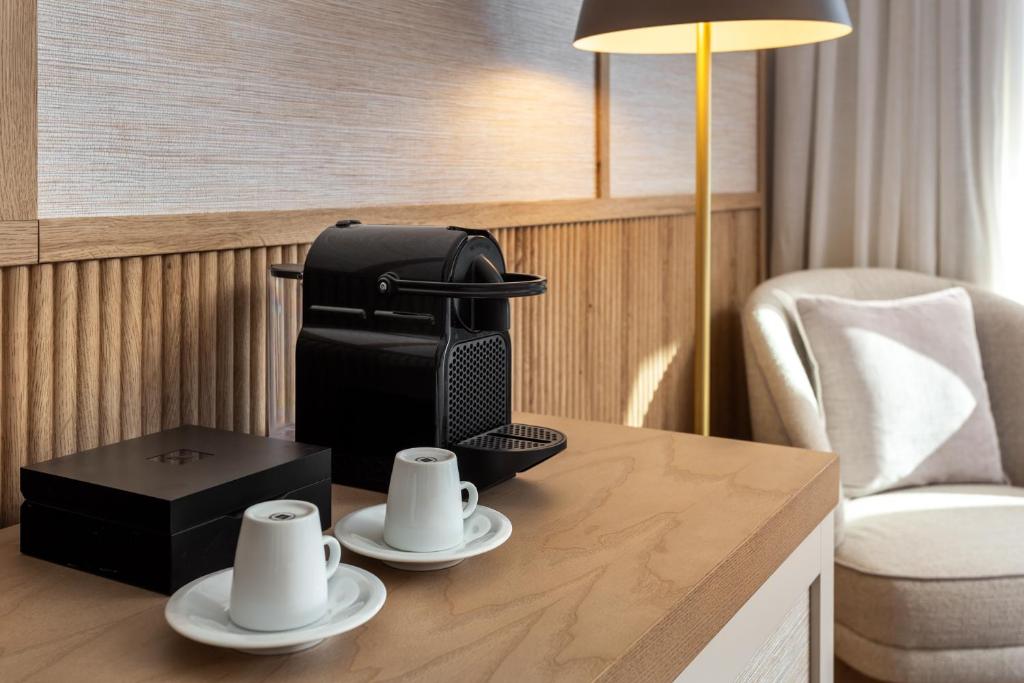 a hotel room with a table with cups and a suitcase at Grande Real Santa Eulalia Resort & Hotel Spa in Albufeira