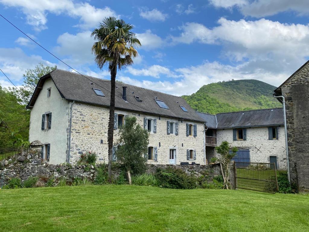 une vieille maison en pierre avec un palmier dans la cour dans l'établissement Chez Castagné, à Issor