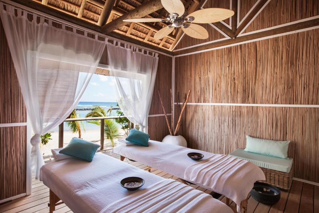 two beds in a room with a view of the ocean at Veranda Pointe Aux Biches Hotel & Spa in Trou aux Biches