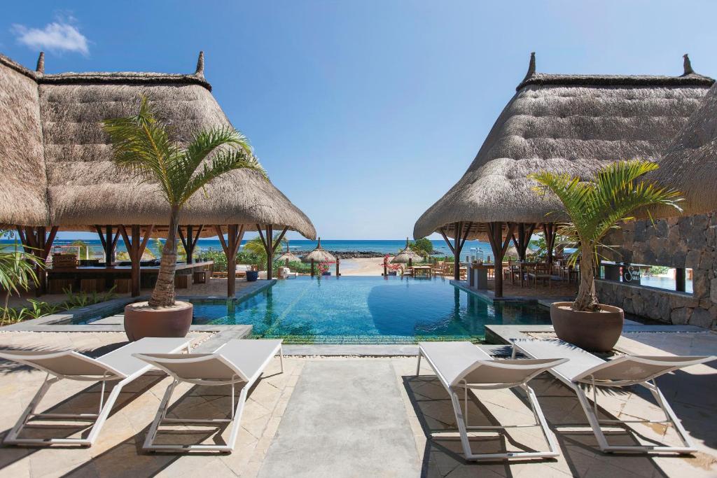 a pool at a resort with chairs and umbrellas at Veranda Pointe Aux Biches Hotel & Spa in Trou aux Biches