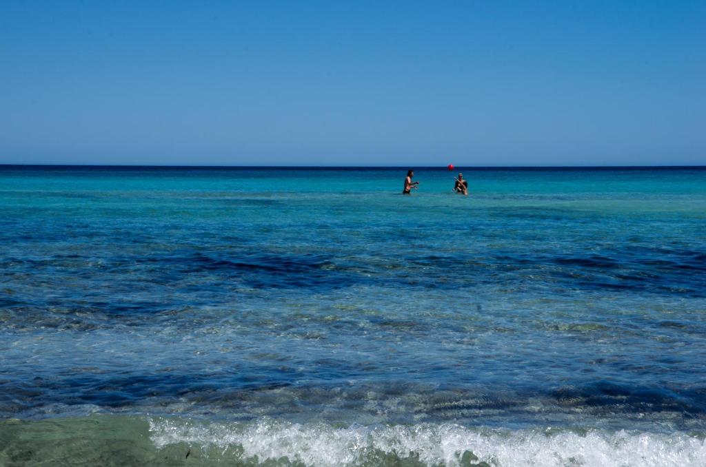 two people walking in the water on the beach at Hotel Fontane Bianche in Fontane Bianche