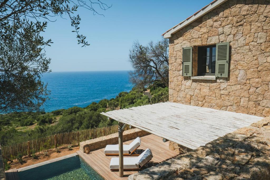 une maison en pierre avec une table et une piscine dans l'établissement Casi di Mare, à Cargèse