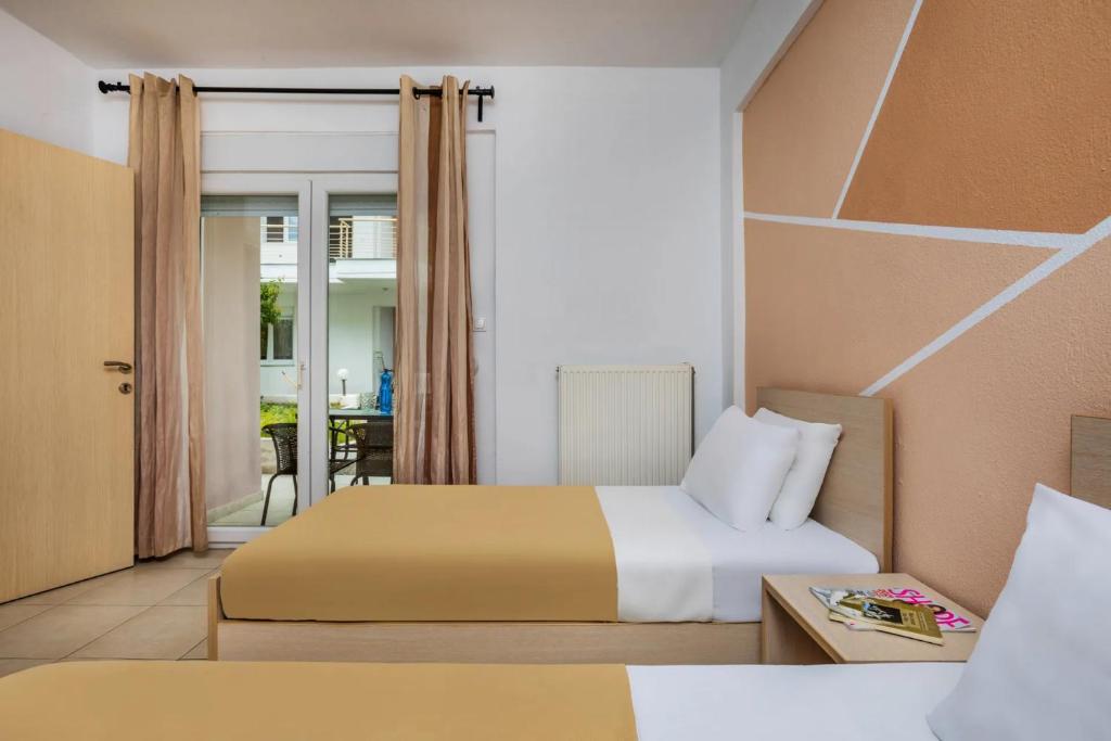 ハニオティスにあるNikiforos Apartmentsのベッド2台とバルコニー付きのホテルの部屋
