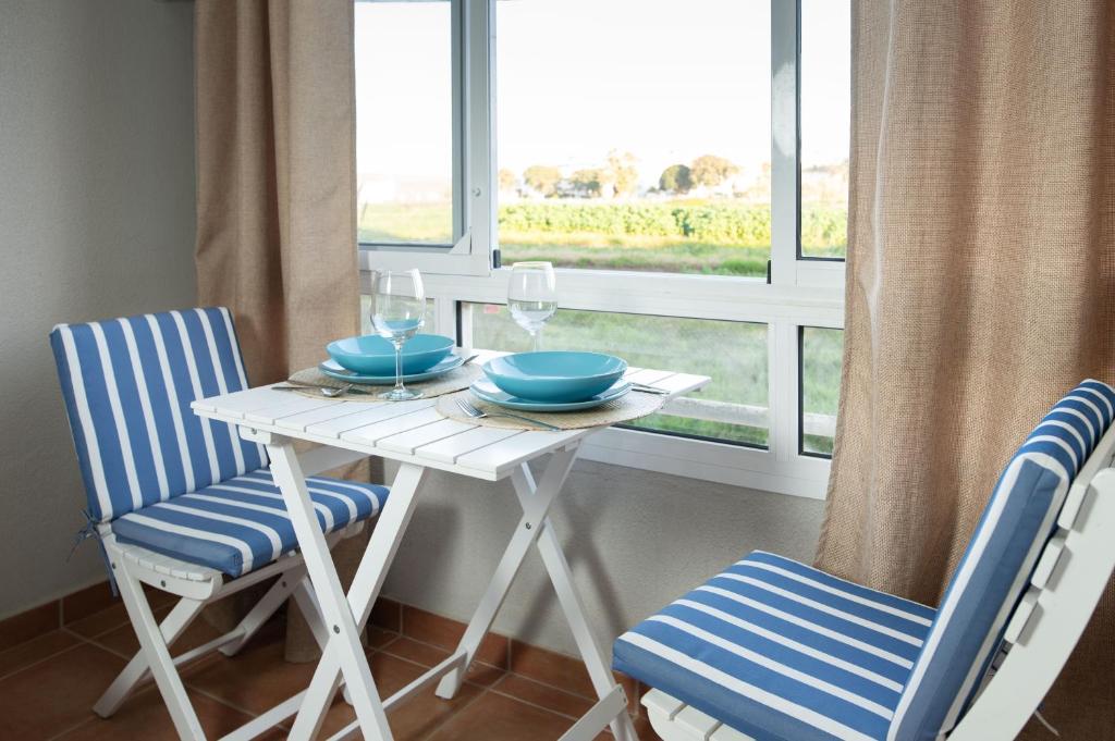 a white table with two blue chairs and a window at Alma de Zahara in Zahara de los Atunes