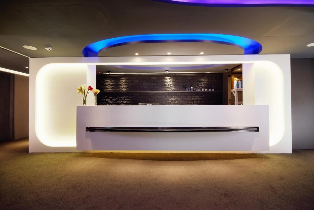 a lobby with a white reception desk with blue lights at Guest Hotel in Taipei