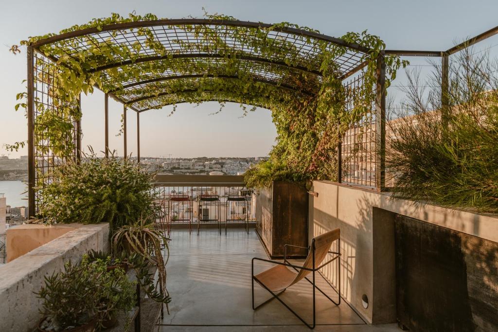 an archway with plants on a building with a chair at SCALA by Valletta Vintage in Valletta