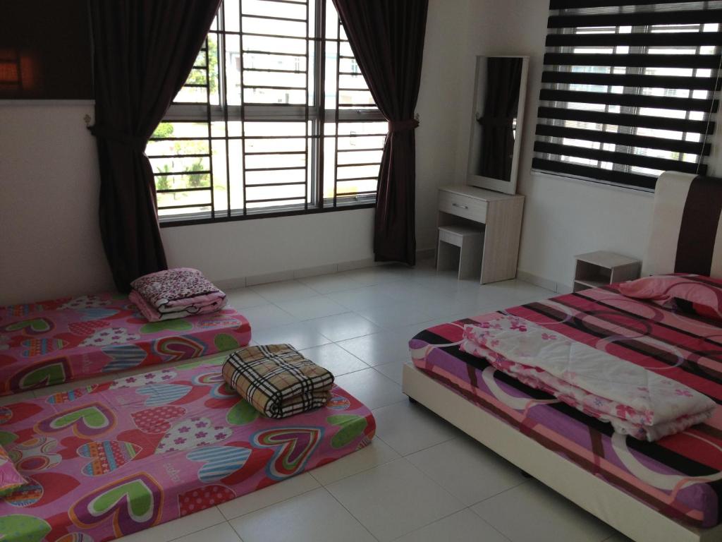 a bedroom with two beds and a television in it at Comfort Holiday Home @ Bukit Indah in Johor Bahru