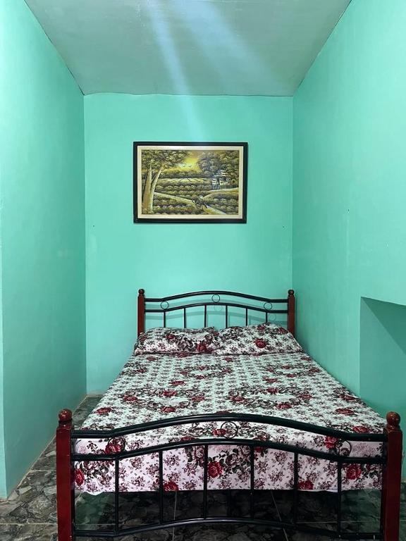 a bed in a blue room with a picture on the wall at Zia's homestay-2 in Siquijor