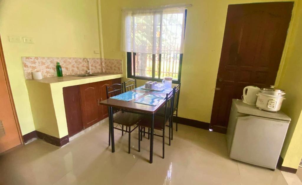 eine kleine Küche mit Tisch und Stühlen und einem Kühlschrank in der Unterkunft Colorful Tropical Bungalow in Bacong