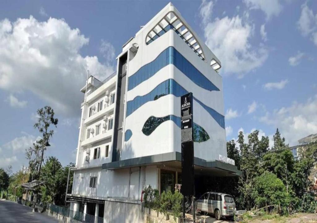 a blue and white building with a car parked in front at Aurora Hotels and Resorts in Pulickamaly