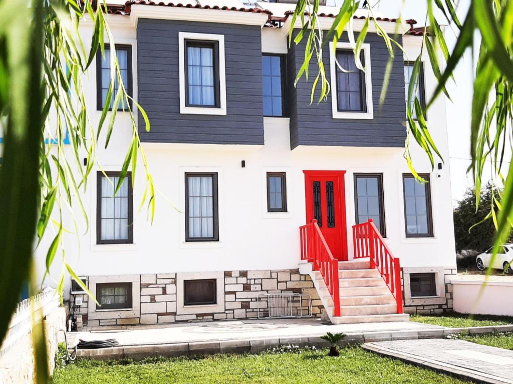 a house with a red door in front of it at QonuQ Bozcaada in Bozcaada