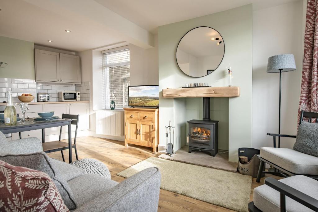 a living room with a fireplace and a table and a mirror at California Cottage in Barnard Castle