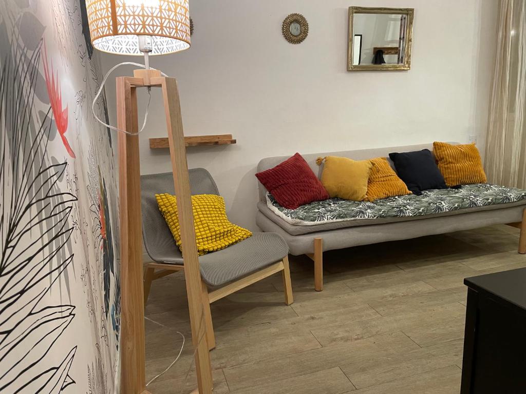- un canapé avec des oreillers colorés et une chaise dans la chambre dans l'établissement Appt 2 chambres au centre ville 3è, à Marseille