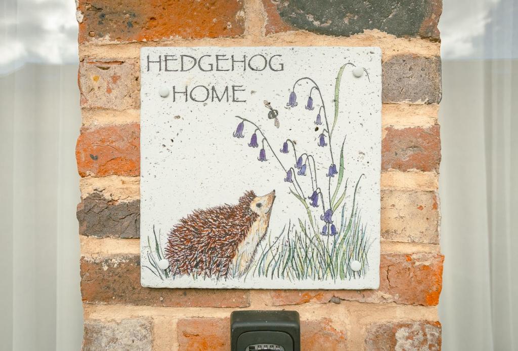 a hedgehog home sign on a brick wall at Hedgehogs Home at Tove Valley Cottages in Towcester