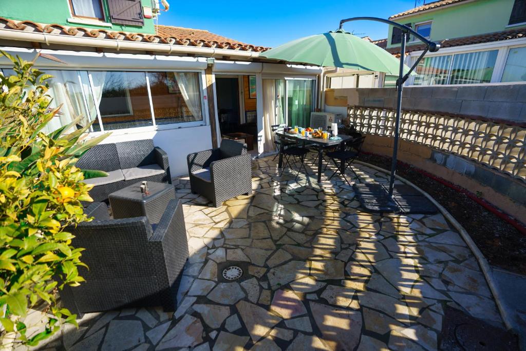 un patio avec des chaises et une table avec un parasol dans l'établissement L'escale des copains, au Barcarès