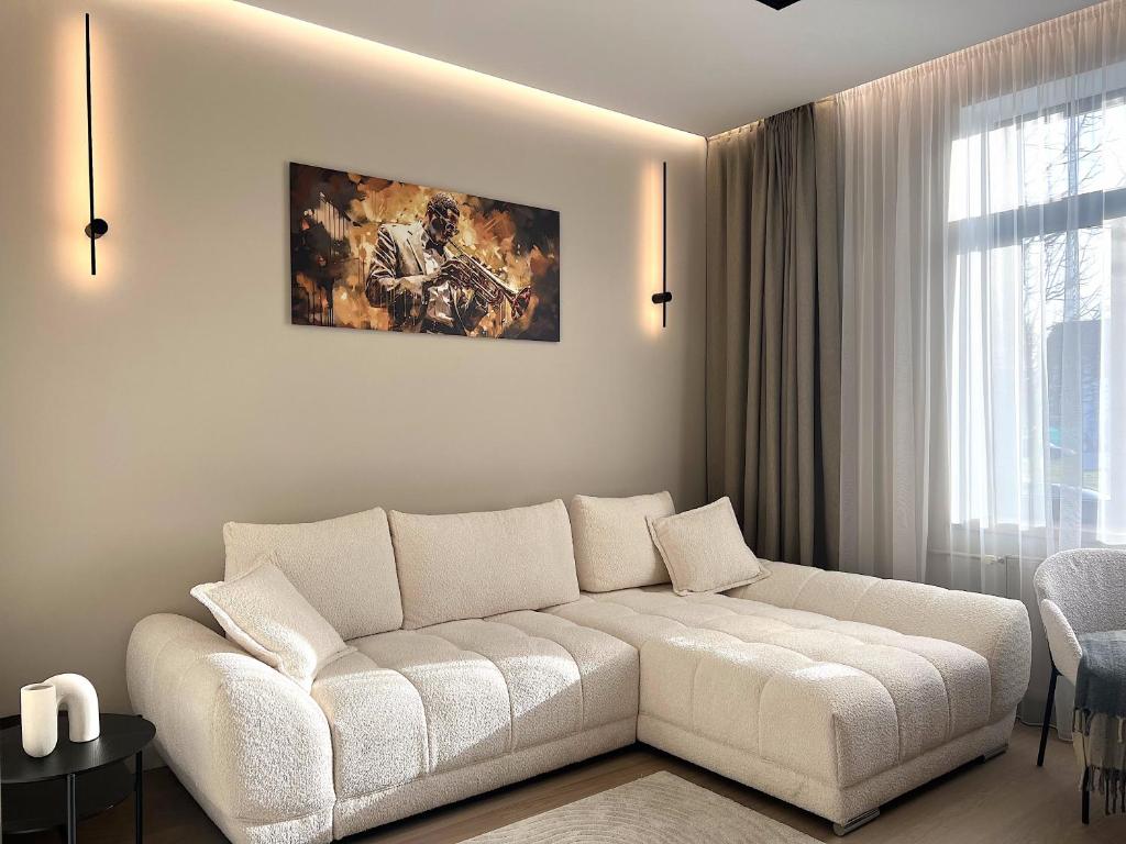ein Wohnzimmer mit einer weißen Couch vor einem Fenster in der Unterkunft Memel Town Apartments in Klaipėda