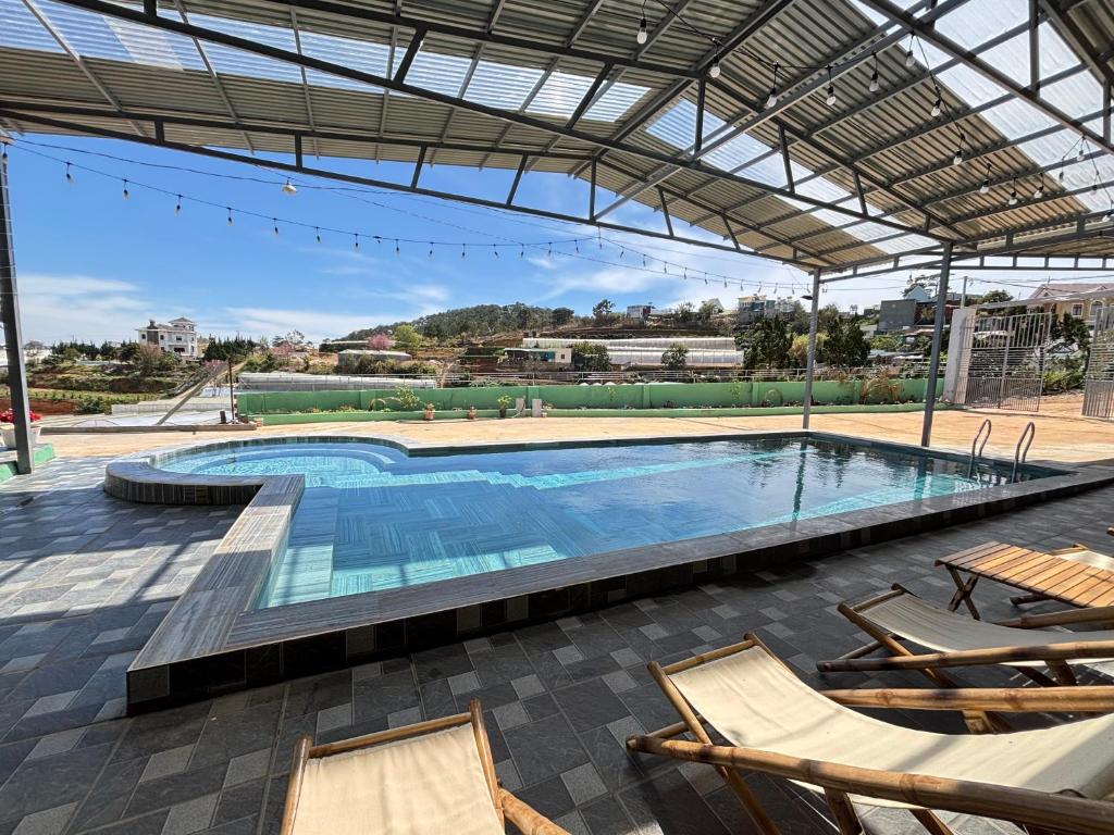 a large swimming pool with chairs and a building at Villa Healing Home - Hồ Bơi Nước Nóng in Trai Mat