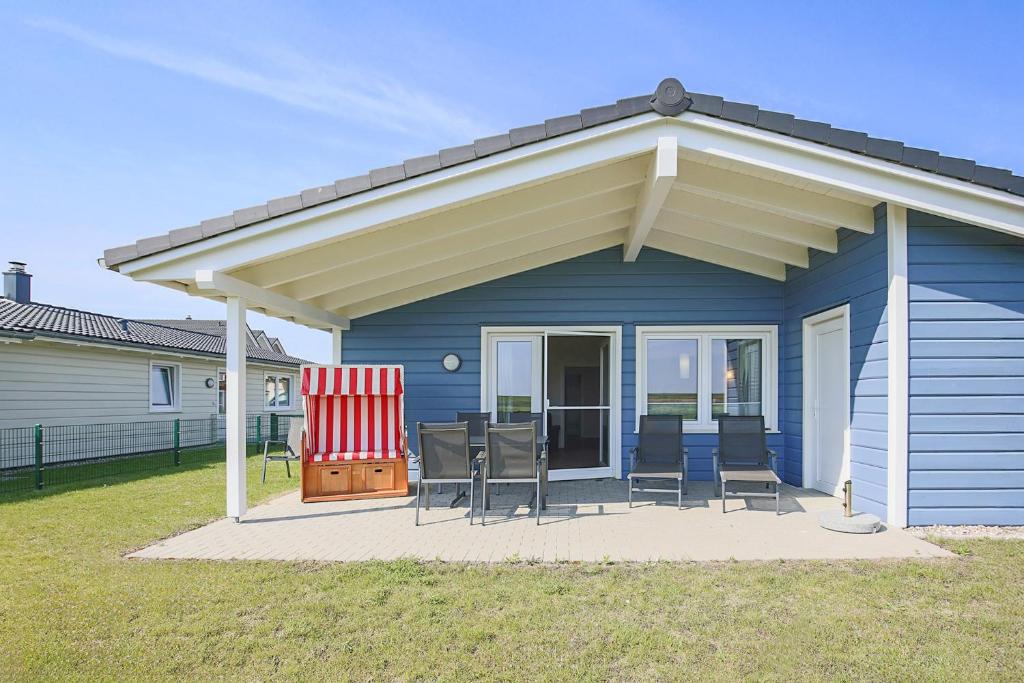 ダゲビュルにあるFerienhaus Herzmuschelのパティオに日よけと椅子が置かれた青い家