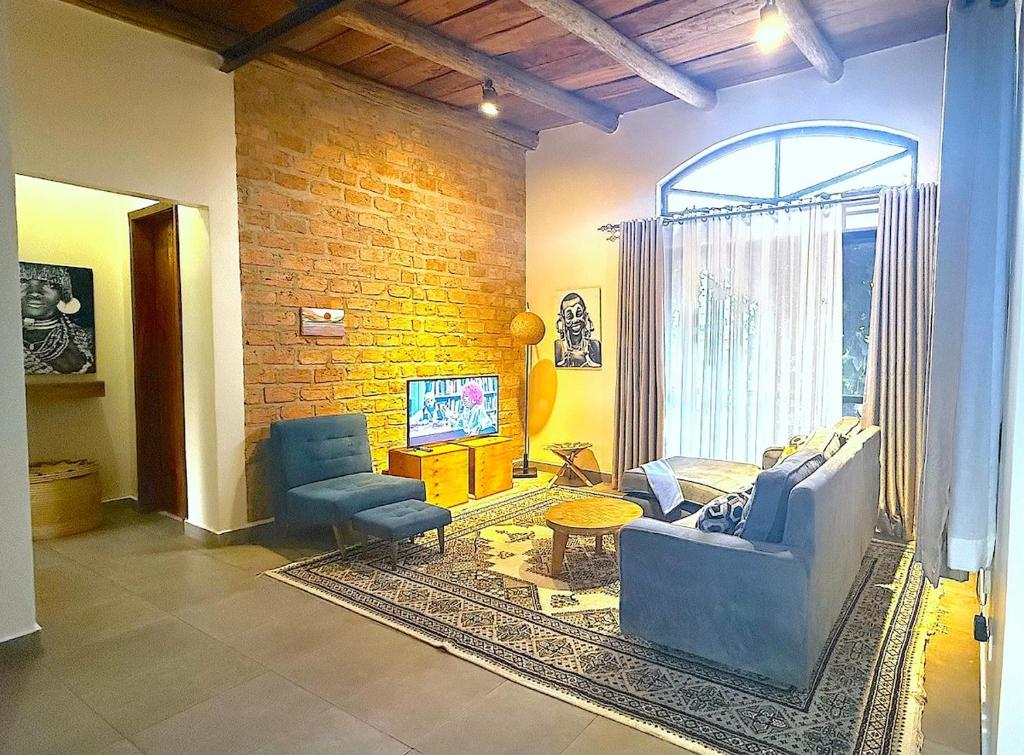 a living room with a couch and chairs and a brick wall at Lush Urbarn Oasis in Kampala