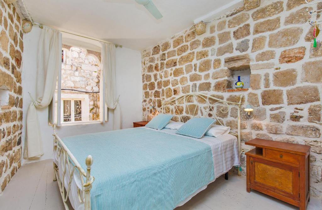 1 dormitorio con 1 cama azul en una pared de piedra en Peti Apartment, en Dubrovnik