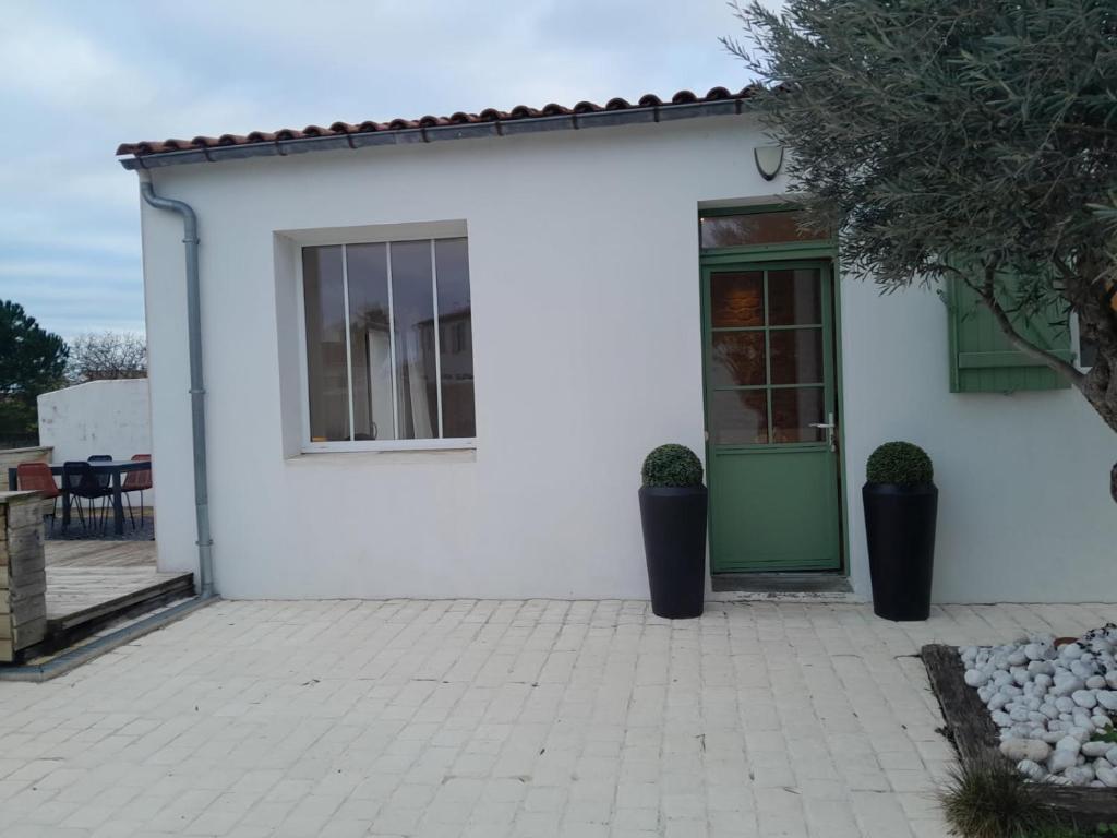 une maison blanche avec une porte verte et une terrasse dans l'établissement La Maison du Clocher, à Rivedoux-Plage