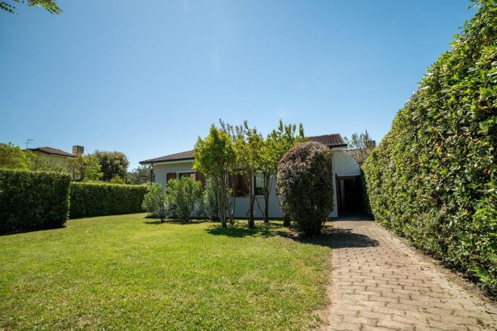 un jardin avec une maison et une haie dans l'établissement Leccio, à Albarella