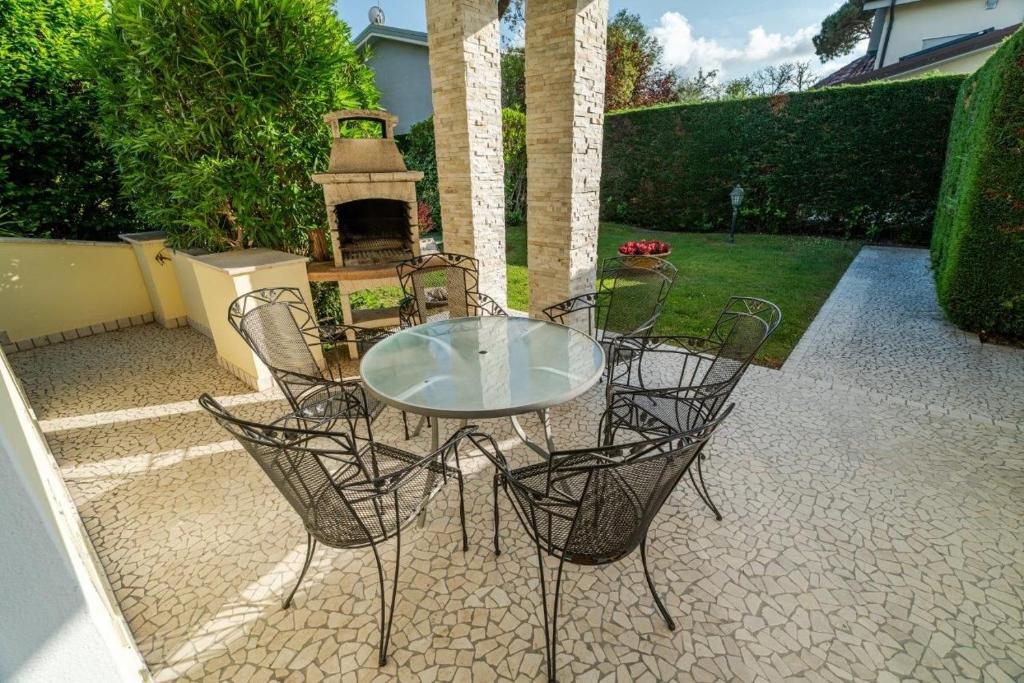 a glass table and chairs on a patio with a fireplace at Diamante in Isola Albarella