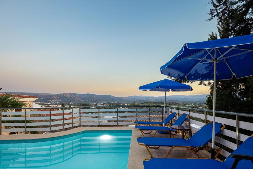 ein Swimmingpool mit blauen Stühlen und Sonnenschirmen in der Unterkunft Bezari pool villa in Metochia Fratzeskiana