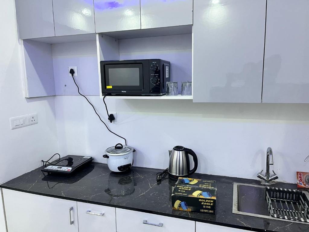 cocina con microondas y TV en la barra en Royal Orbit studio, en Noida