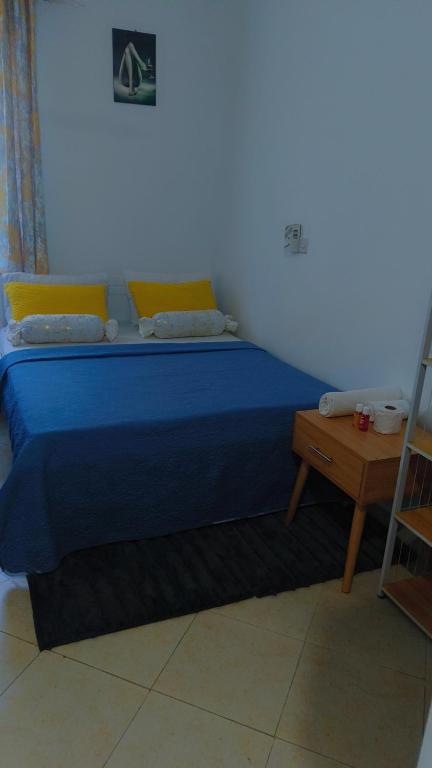 a bedroom with a blue bed and a table at Pro Marcus studio apartment in Mtwapa