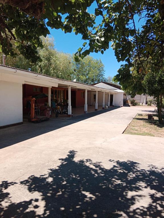 a large white building with a tree in the foreground at Comodo Hostal para personas de trabajo in Linares