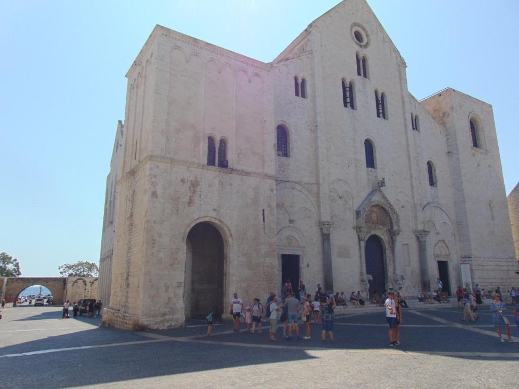 un gruppo di persone che si trovano fuori da un grande edificio di Dimora Santi e Marinai a Bari