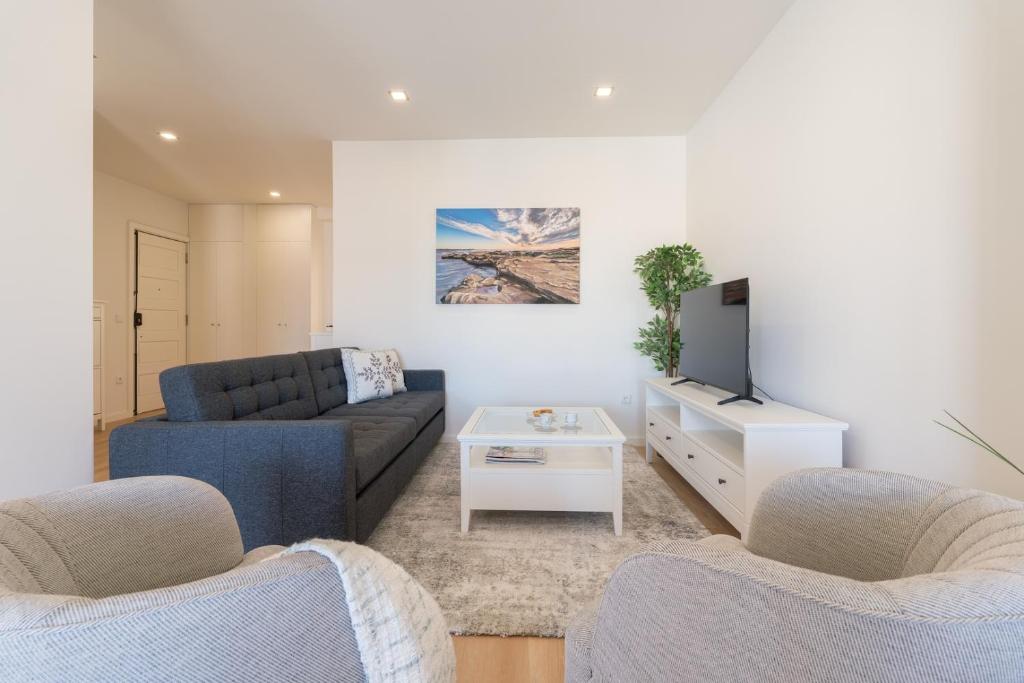 a living room with a couch and a tv at Bright & Spacious Retreat with Balcony by HostWise in Porto