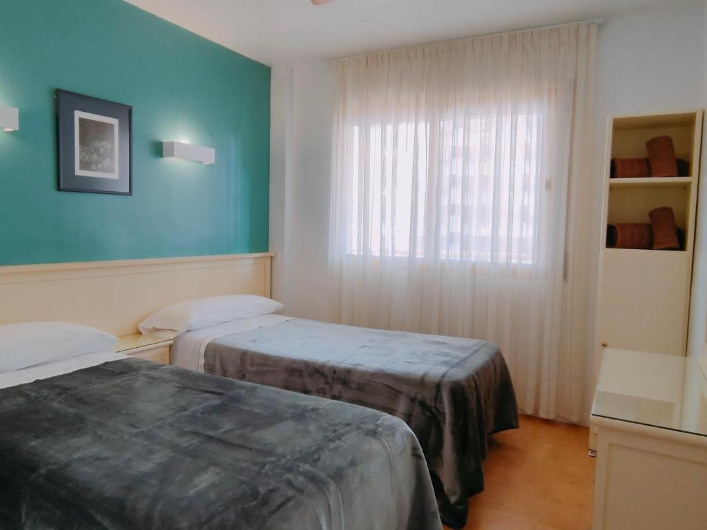 a hotel room with two beds and a window at Apartamentos Eldorado in Lloret de Mar