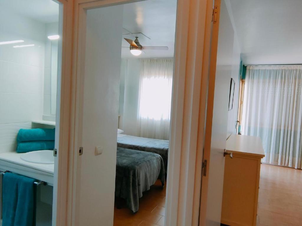 a room with a bed and a bathroom with a mirror at Apartamentos Eldorado in Lloret de Mar