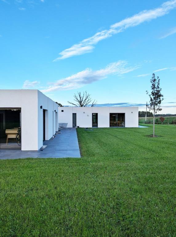a white building with a green field in front of it at Maisons du lac in Écollemont
