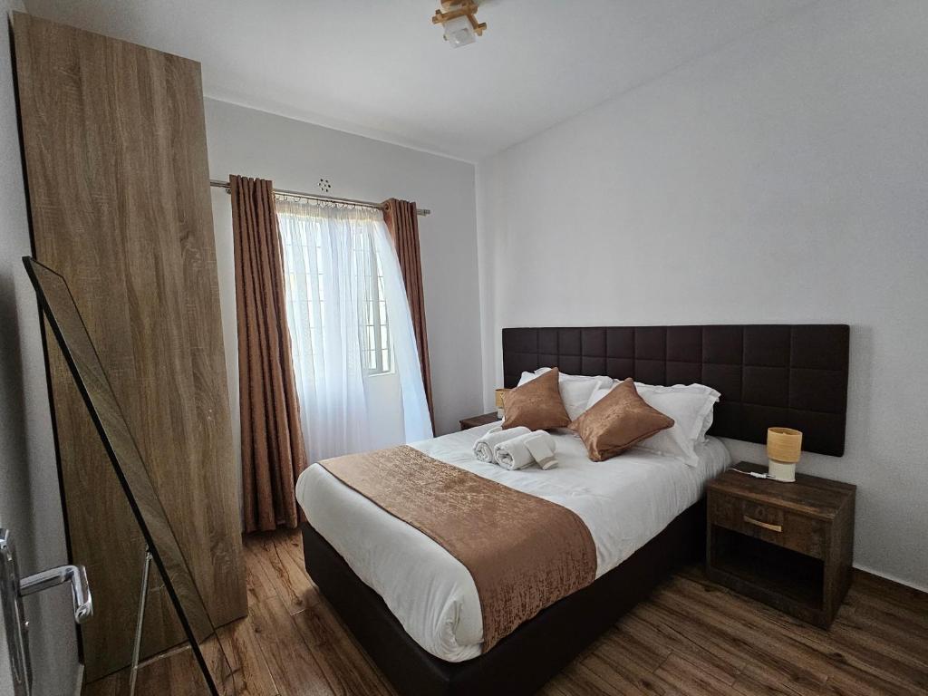 ein Schlafzimmer mit einem großen Bett und einem Fenster in der Unterkunft orana homes II in Ruiru